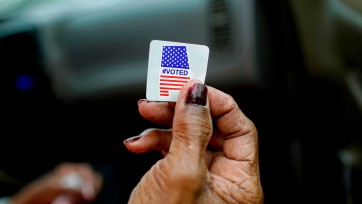 a hand holds an Alabama voting sticker