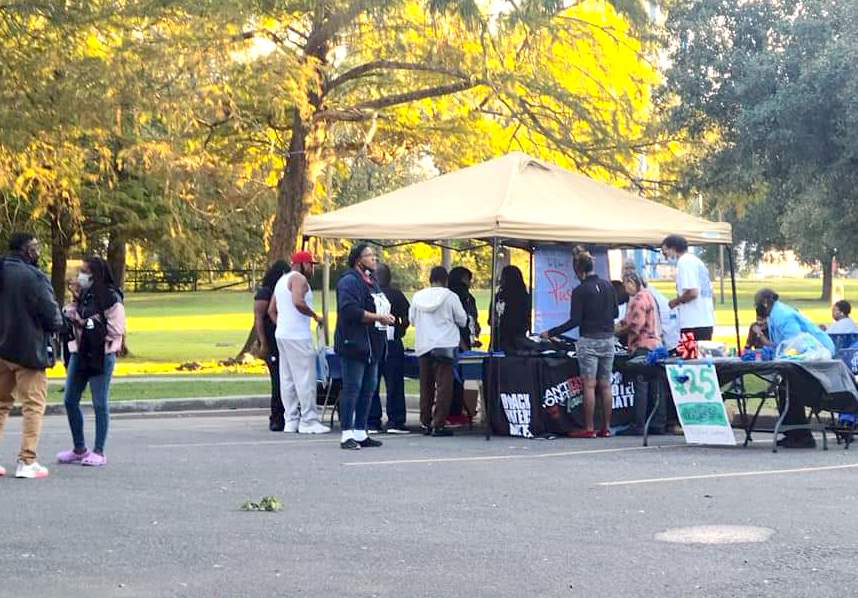 People are gathered under a tent at a Louisiana voting rights rally.